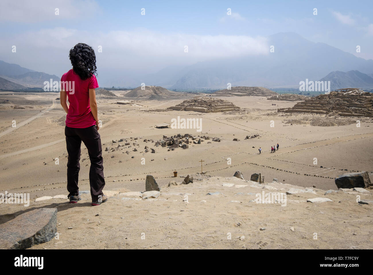Visitatore femmina guardando dal di sopra della suggestiva città sacra di Caral in Barranca Provincia, Regione di Lima, Perù Foto Stock