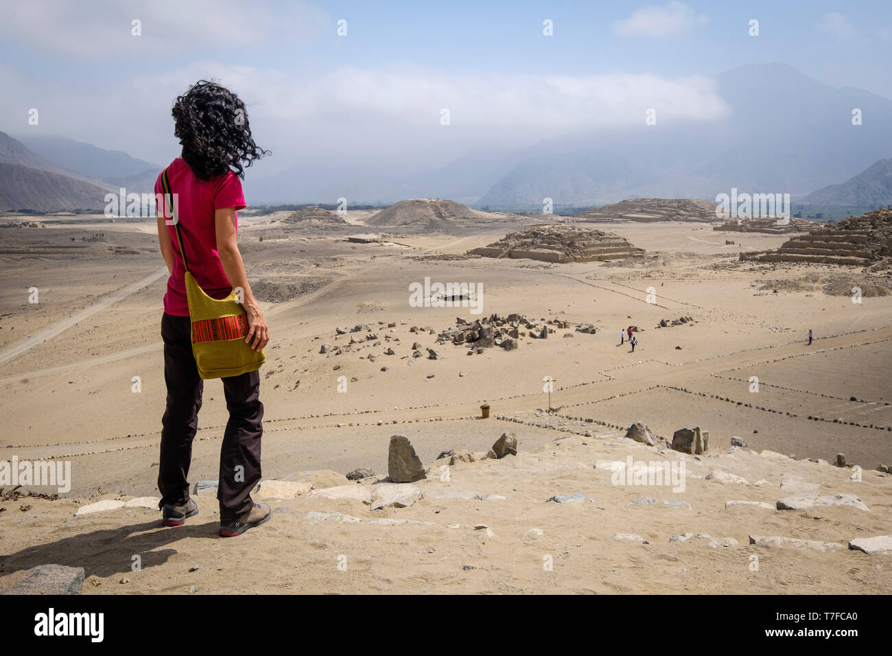 Visitatore femmina guardando dal di sopra della suggestiva città sacra di Caral in Barranca Provincia, Regione di Lima, Perù Foto Stock