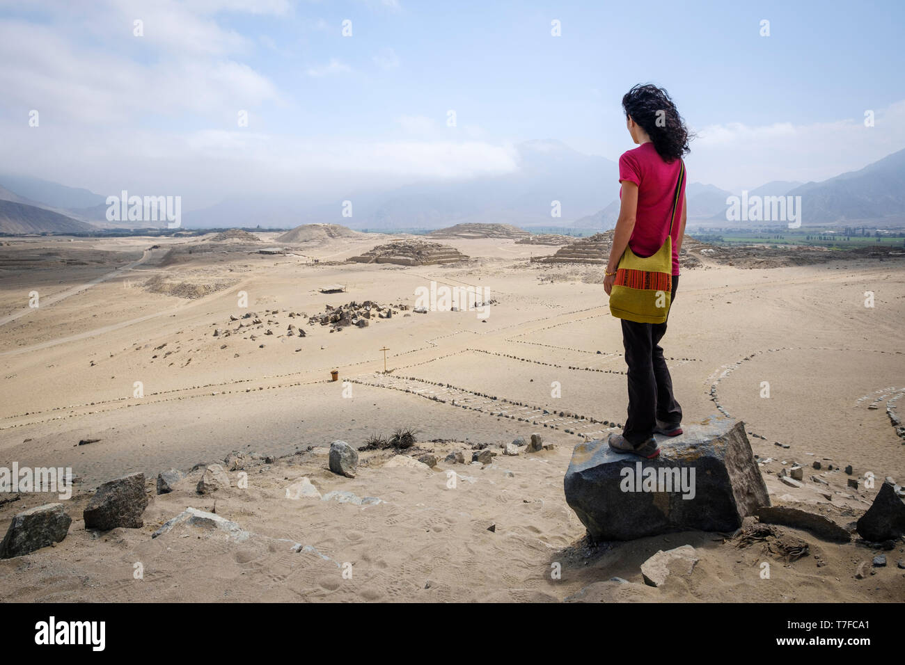 Visitatore femmina guardando dal di sopra della suggestiva città sacra di Caral in Barranca Provincia, Regione di Lima, Perù Foto Stock