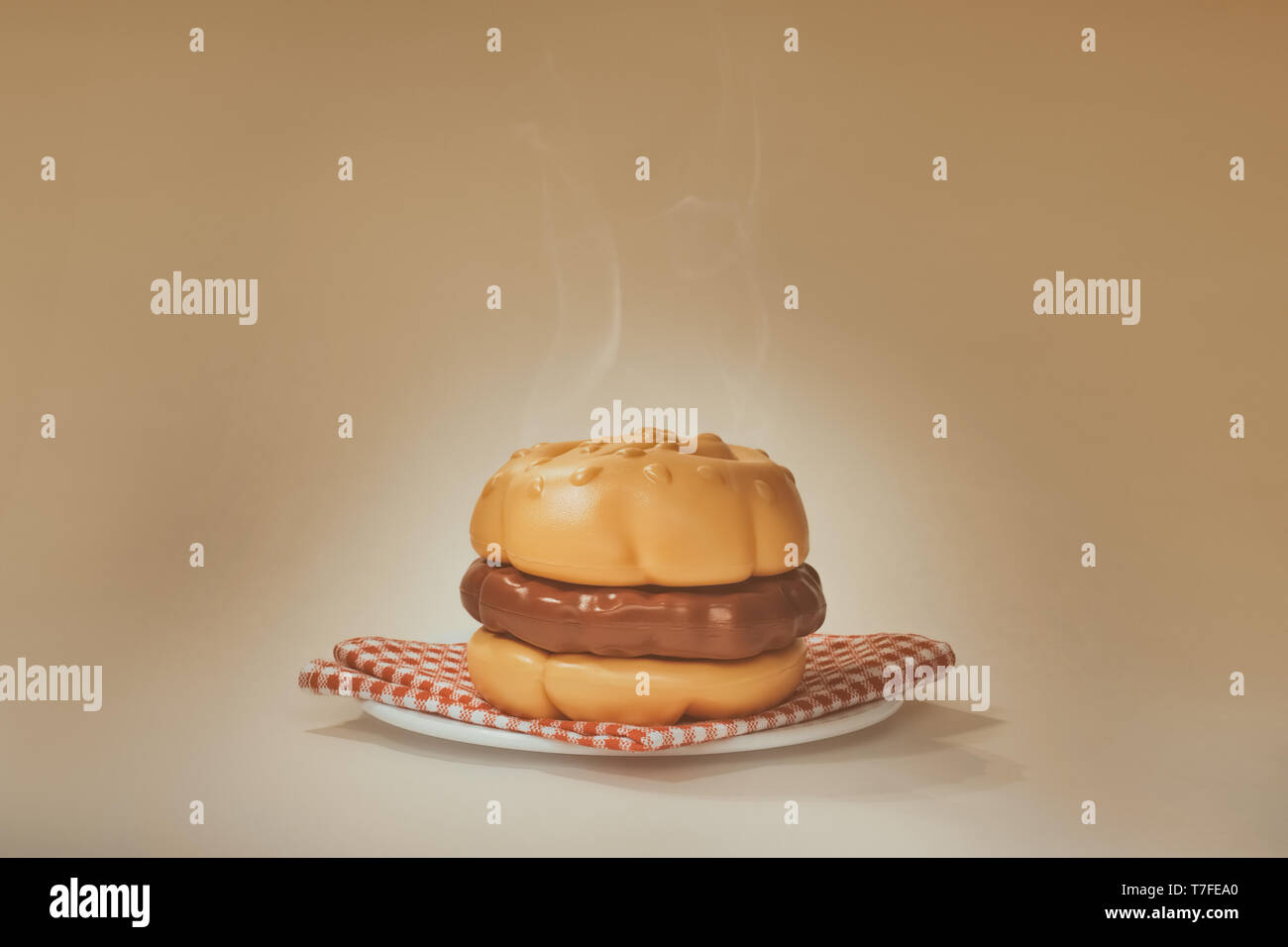 Una fumante Hamburger di plastica su una piastra bianca con tovagliolo a scacchi. Caldo sfondo senza giunture. Foto Stock