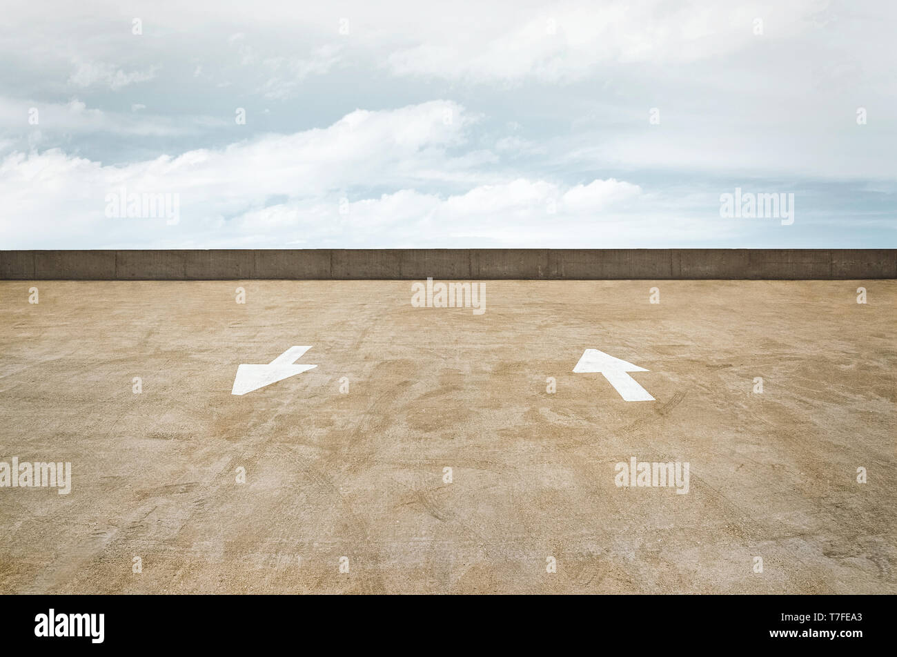 Traffico direzionale frecce su un calcestruzzo garage tetto con un cielo nuvoloso. Foto Stock