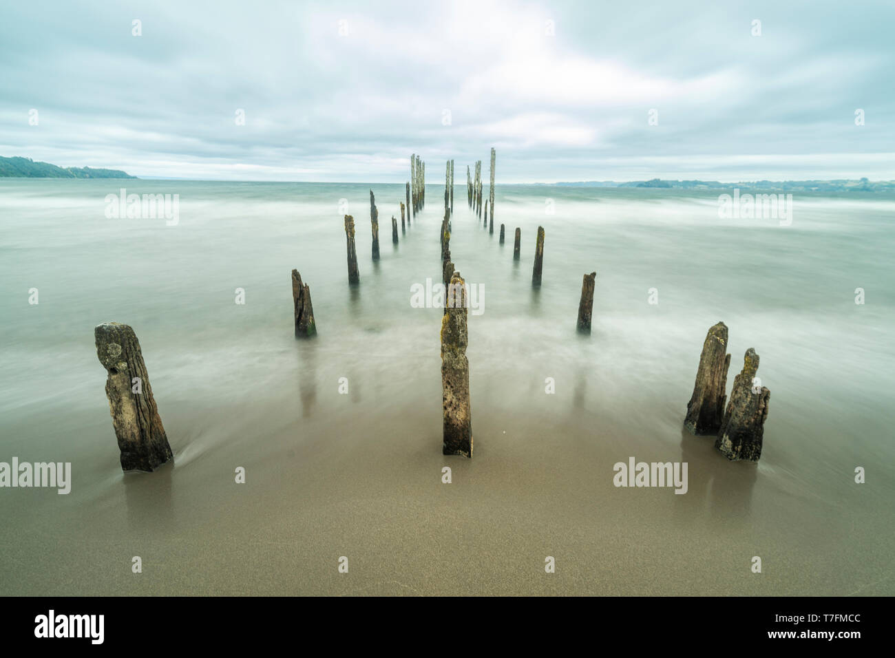 Come una strada per l'inferno un molo vecchio all'interno del lago di acque sotto un drammatico cielo nuvoloso e venti alti. I vecchi pali in legno ancora lotta contro il tempo Foto Stock