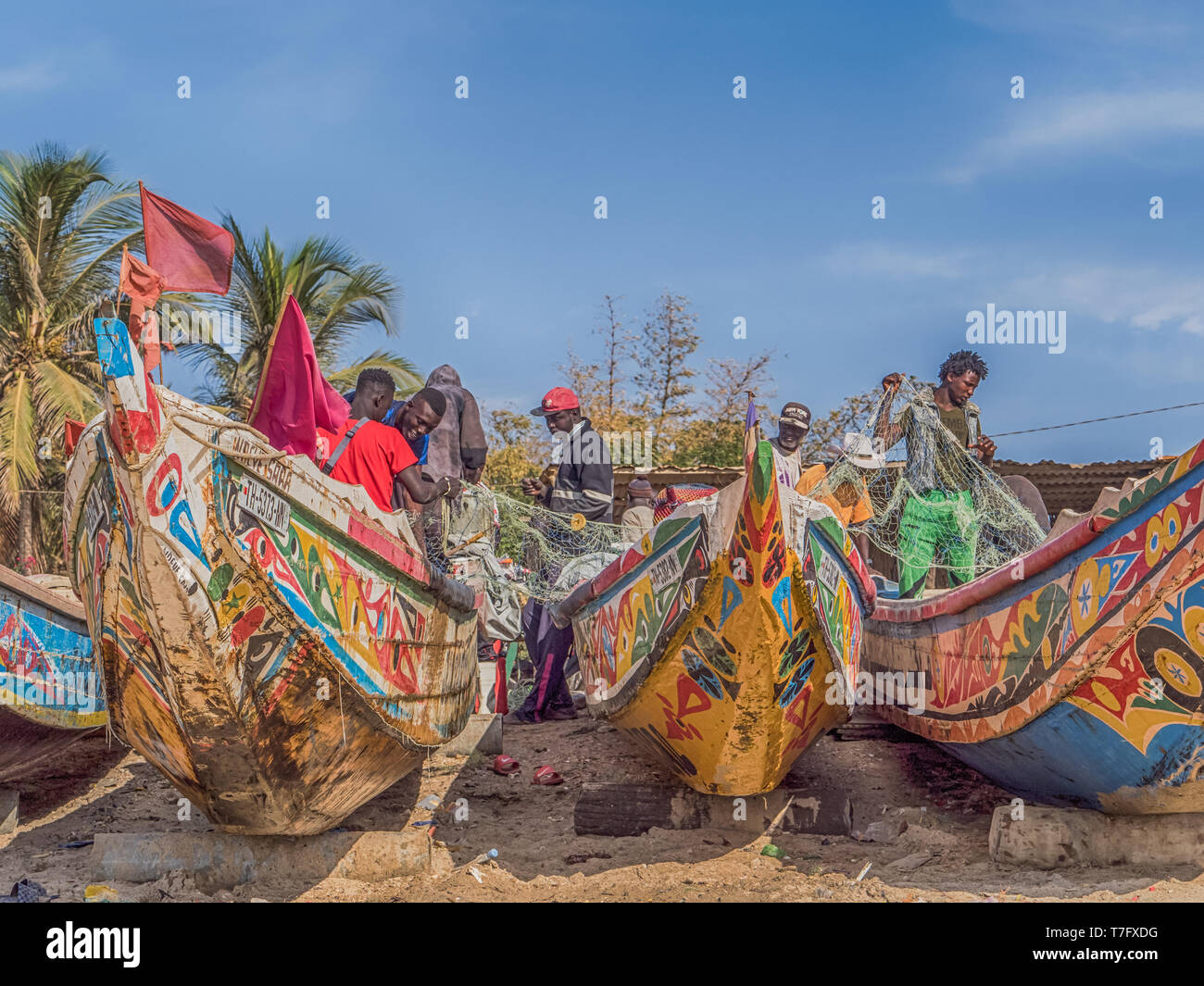 Nianing, Senegal - Gennaio 2, 2019: i pescatori la raccolta di pesce di legno colorato barca fisher permanente sulla spiaggia. Africa Foto Stock