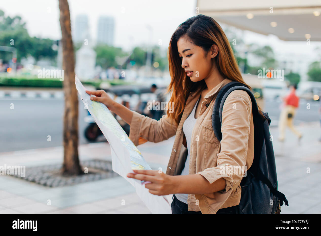 Piuttosto casual donna asiatica con zaino carta di lettura mappa mentre esplorate la città di Bangkok, Thailandia Foto Stock