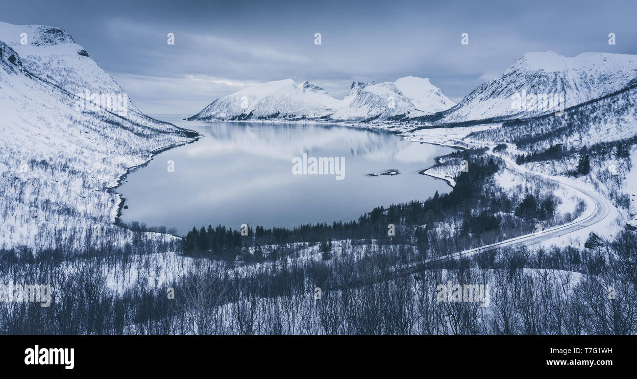 Sera d'inverno al fiordo Bergsbotn. Montagne coperte di neve che si innalzano per oltre fredde acque del mare del Nord Foto Stock