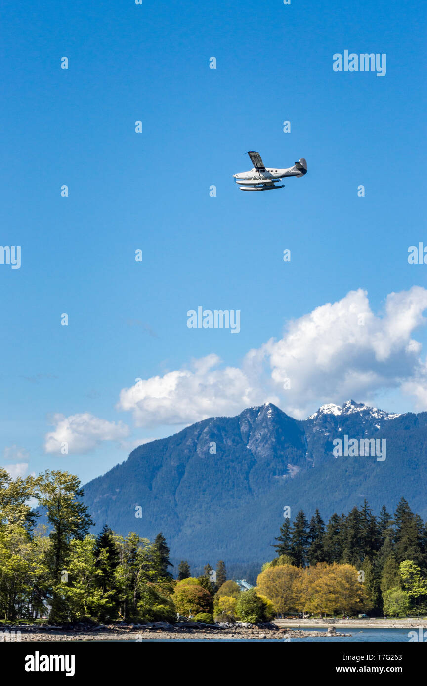 Vancouver, BC - 5 Maggio 2019: Fairmont Hotel piano di " commuters " flying ovest di sopra di Coal Harbour. Stanley Park e North Shore Mountains in background. Foto Stock