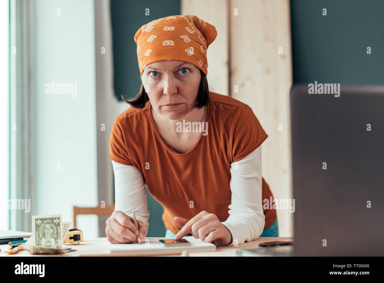 Falegname femmina con il fazzoletto di testa facendo il calcolo finanziario in falegnameria officina di falegnameria Foto Stock