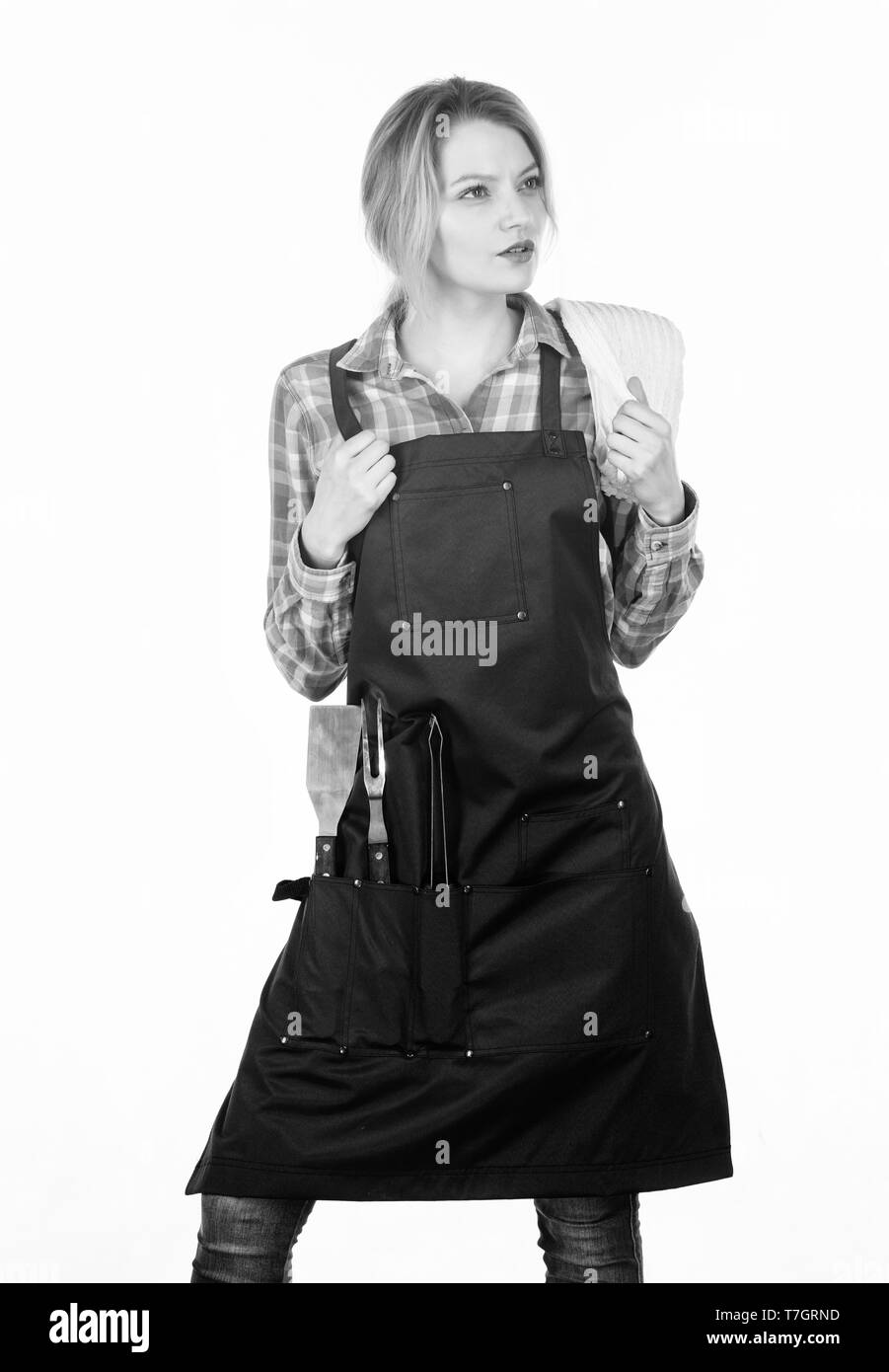 La cottura alla griglia di cibi. La cottura della carne a bassa temperatura per lungo tempo all'aperto. Per picnic e barbecue. La cottura della carne nel parco. Barbecue master. Donna Camicia a scacchi e grembiule per la cottura di sfondo bianco. Foto Stock