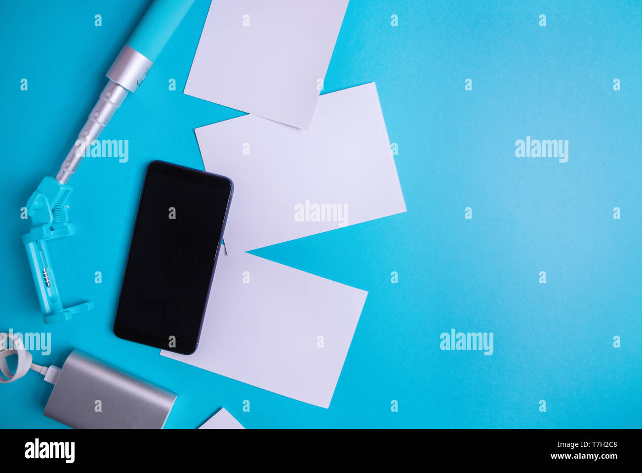 Smartphone con schermo vuoto e volantini e foto su uno sfondo blu. Mock up, laici piatta Foto Stock