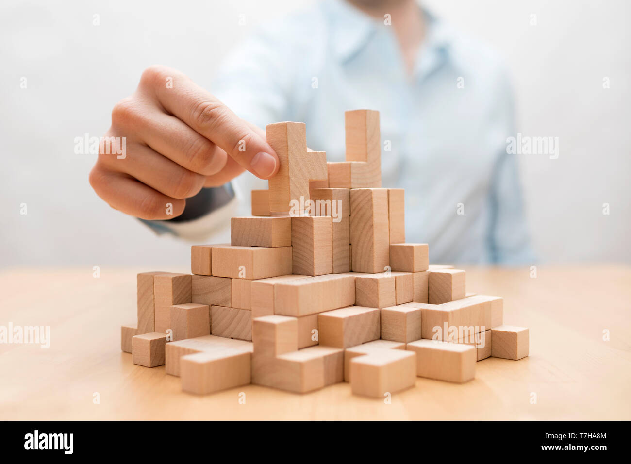 Mano d'uomo di impilamento dei blocchi di legno. Business development concept Foto Stock