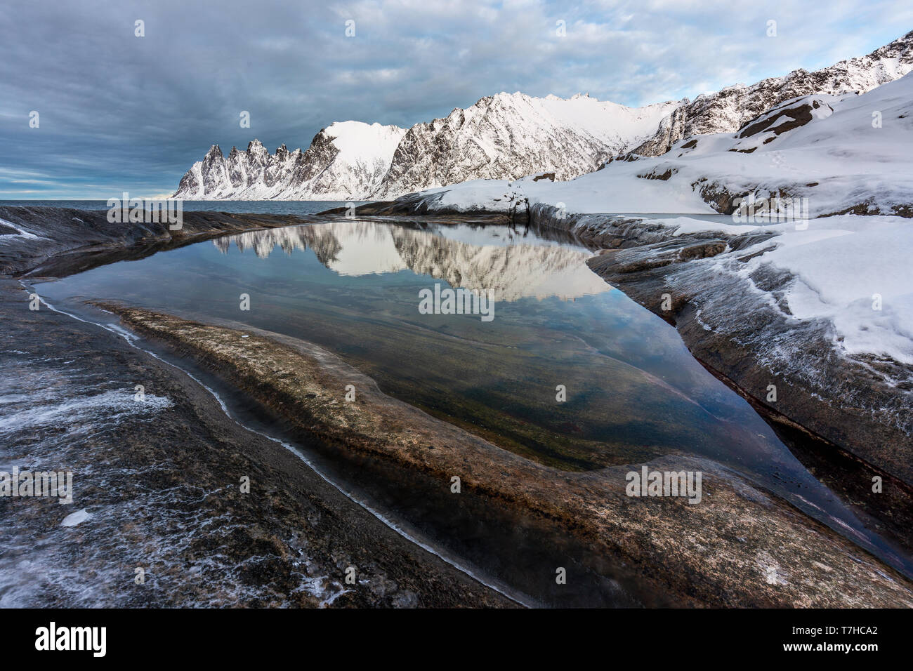 Montagne innevate gamma di Tungeneset, Norvegia. Montagne Distand riflessa in riva di stagno Foto Stock