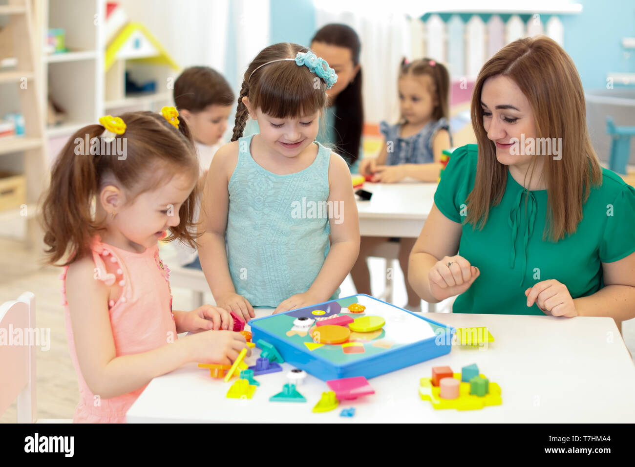 Bambini bambini e insegnante giocando con il costruttore di tabella in kindergarten Foto Stock