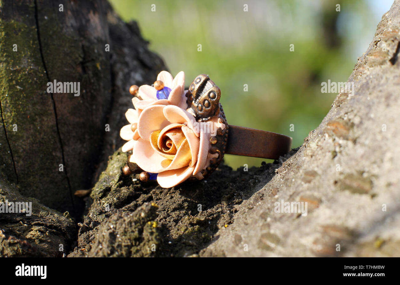 Un fatto a mano anello in una forma di fiori da polymer clay su sfondo di legno Foto Stock