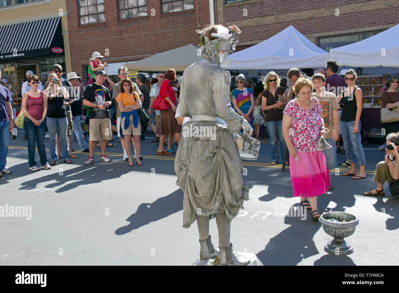 ASHEVILLE, North Carolina, Stati Uniti d'America - 9/5/2010: una famosa statua umana busker noto come il batterista argento ragazza intrattiene la folla in strada come lei detiene Foto Stock