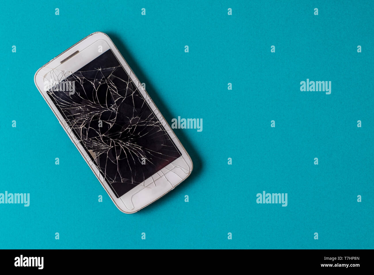 Rotto il telefono cellulare con display rotto su sfondo aqua, piatto laici. Foto Stock