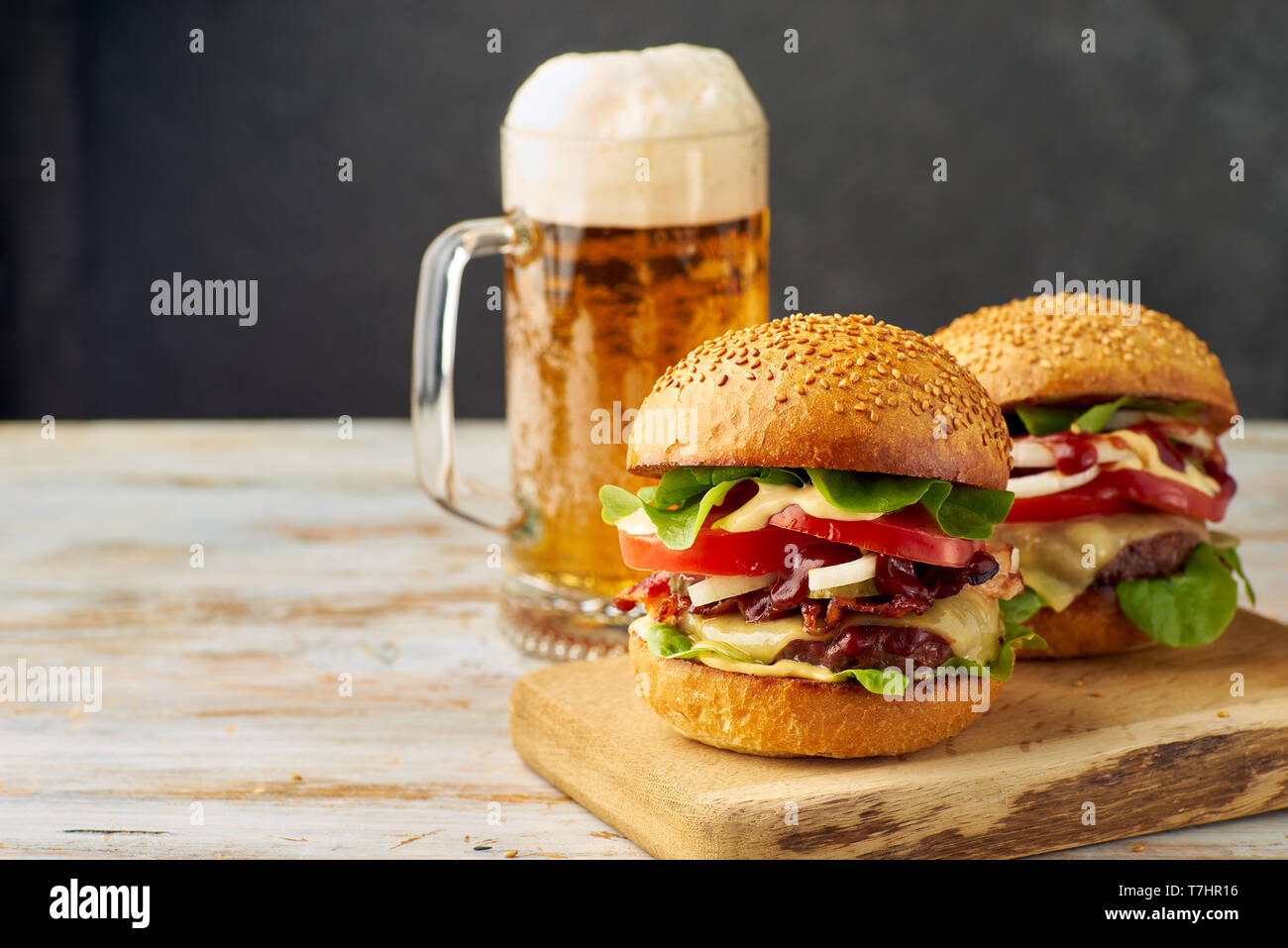 Due grandi hamburger e pinta di birra sul vecchio tavolo in legno Foto Stock