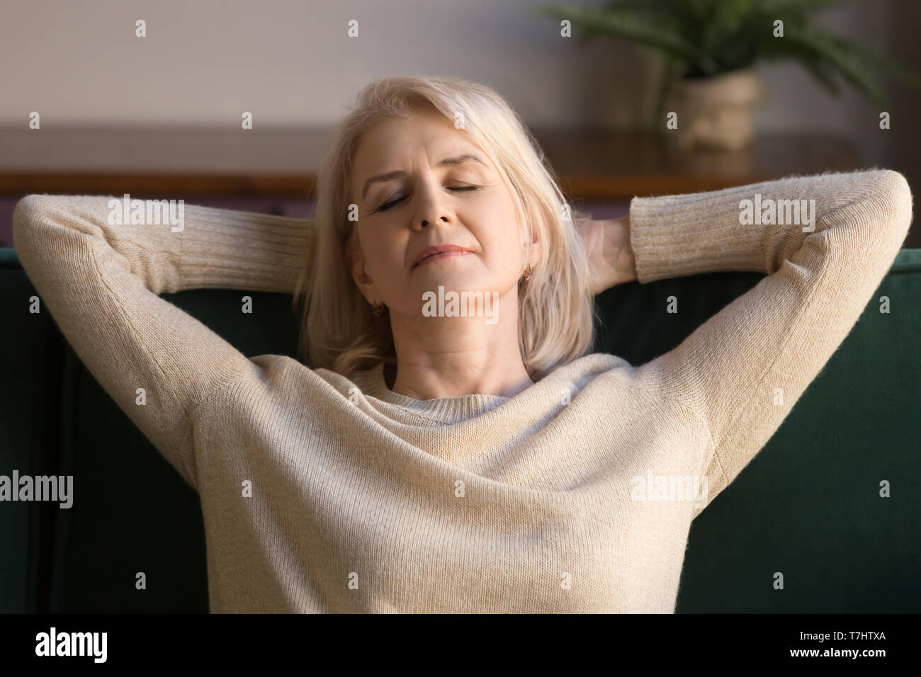 Calma donna di mezza età rilassante godendo weekend sul divano confortevole Foto Stock