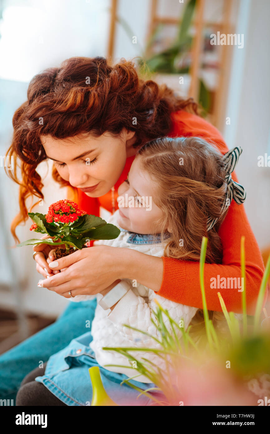 Carino madre e figlia e profumati fiori di casa insieme Foto Stock