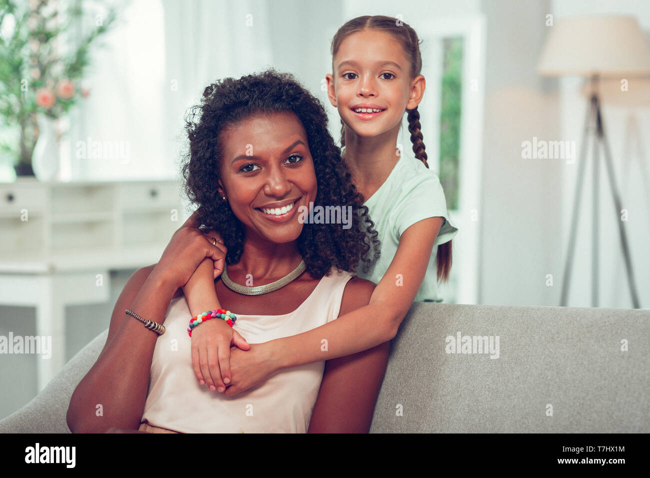 Carino piccola figlia di affetto abbraccio incandescente afroamericana mom. Foto Stock