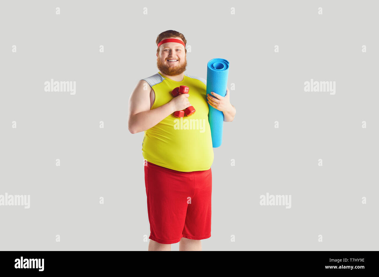 Il grasso funny man con manubri in piedi per lo sport. Foto Stock