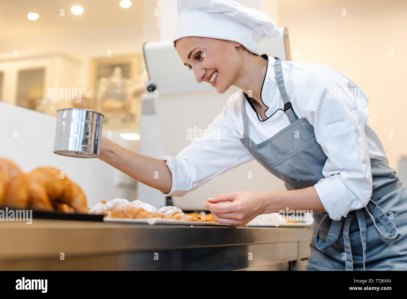 Pasticcere donna la polverizzazione di cacao su pane dolce Foto Stock