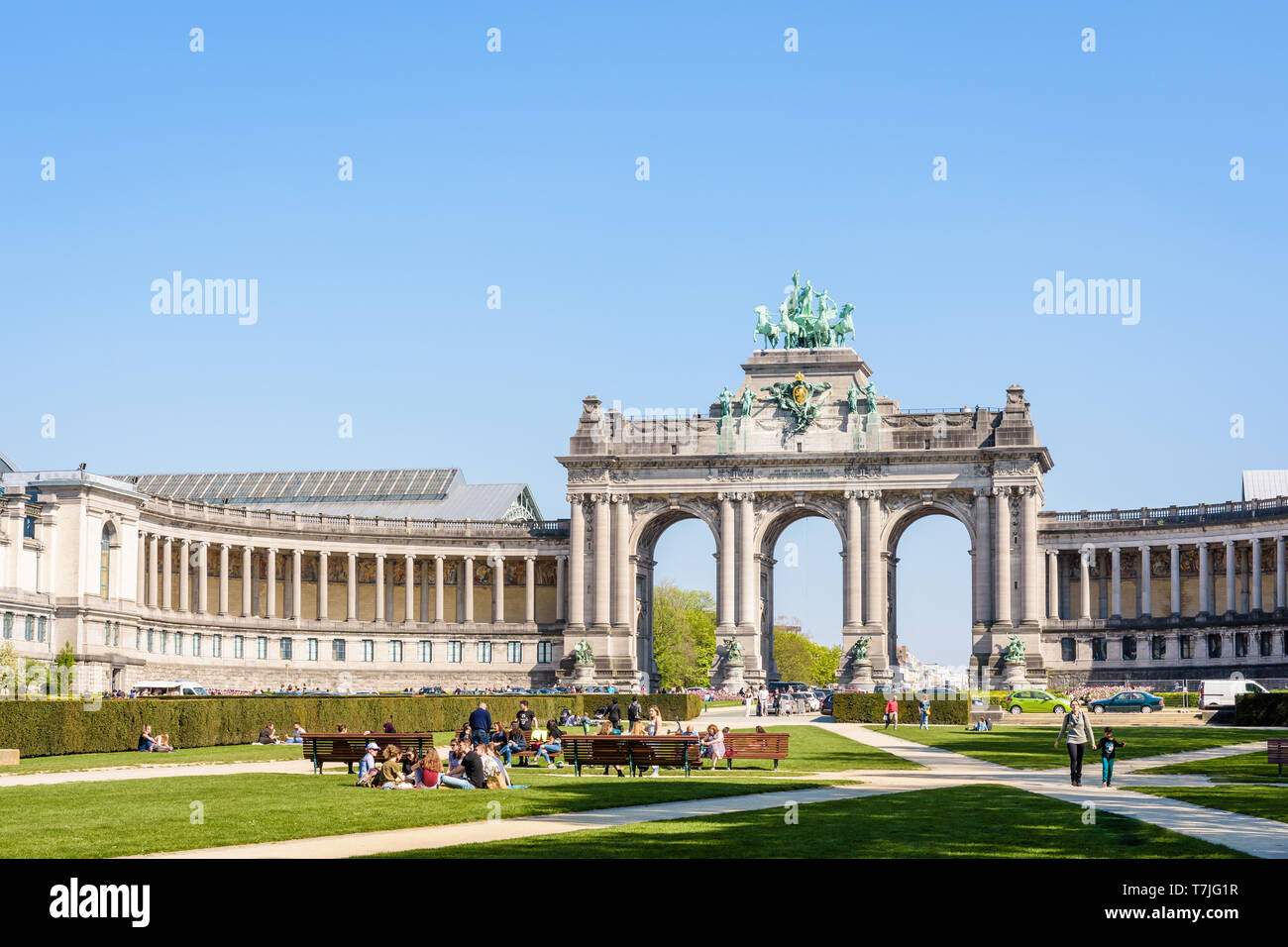 Le persone godono di una giornata di sole nel parco del Cinquantenario a Bruxelles, Belgio, con porticato du Cinquantenaire, l'arco trionfale, in background. Foto Stock