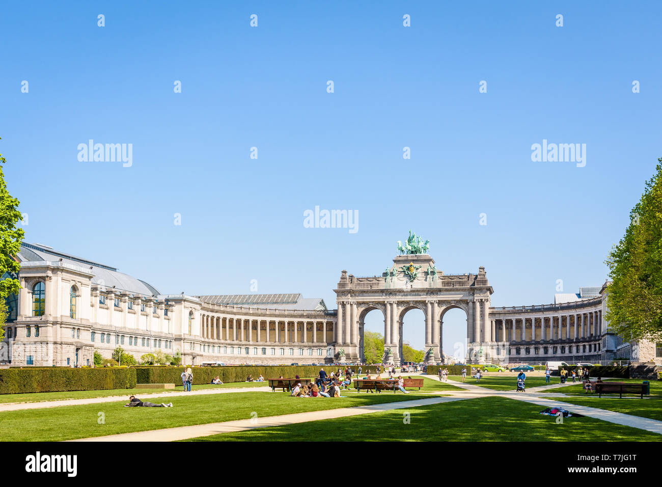 Le persone godono di una giornata di sole nel parco del Cinquantenario a Bruxelles, Belgio, con porticato du Cinquantenaire, l'arco trionfale, in background. Foto Stock
