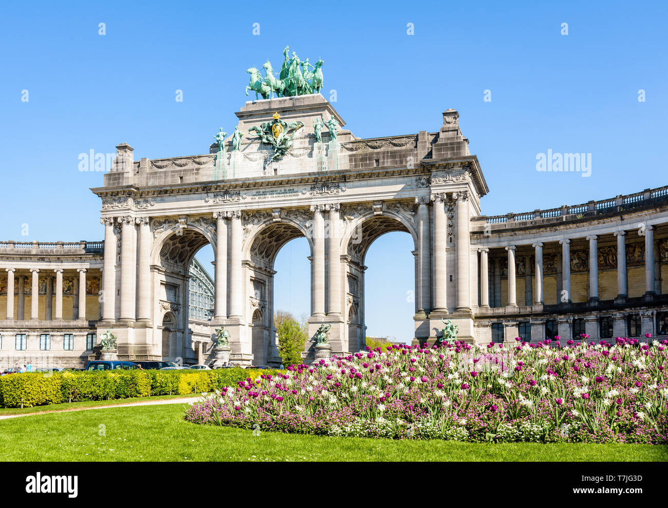 Il arcade du Cinquantenaire, l'arco trionfale nel parco del Cinquantenario a Bruxelles, in Belgio, con un aiuola di fiori in piena fioritura in primo piano. Foto Stock
