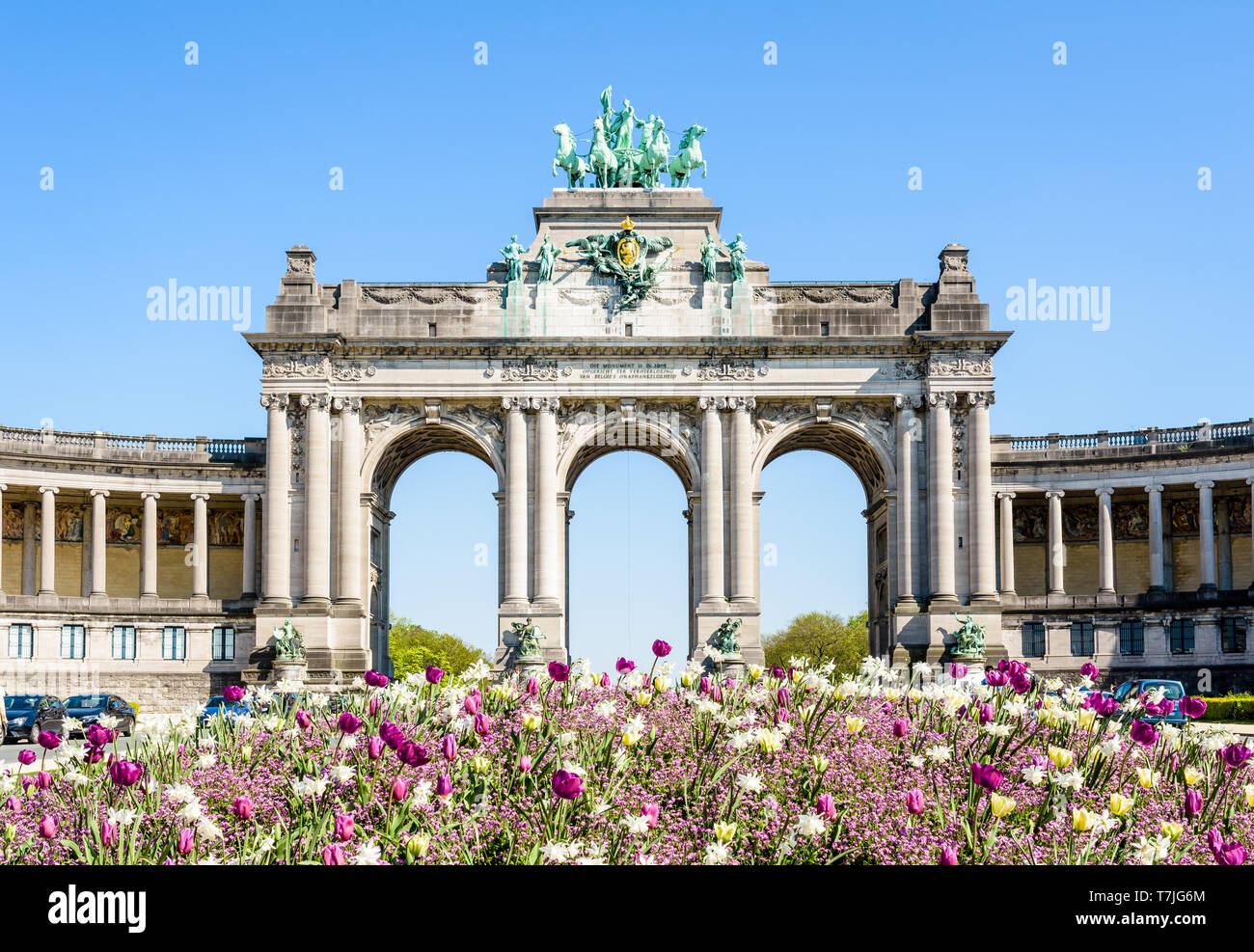 Il arcade du Cinquantenaire, l'arco trionfale nel parco del Cinquantenario a Bruxelles, in Belgio, con un aiuola di fiori in piena fioritura in primo piano. Foto Stock