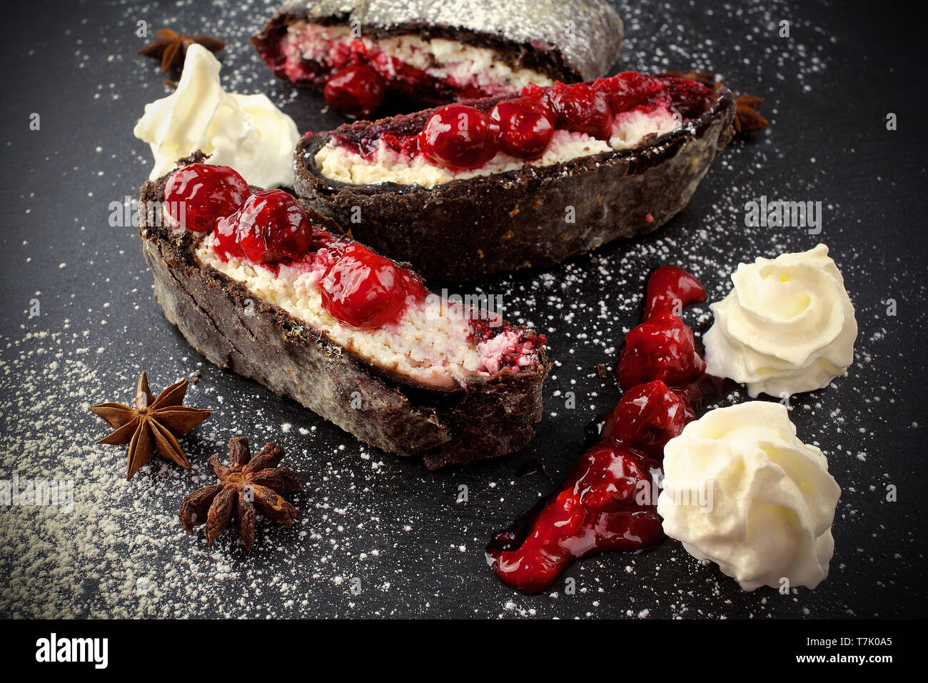 Strudel con una ciliegia. Torta di ciliegie. Grafico a torta, strudel con bacche su sfondo nero Foto Stock