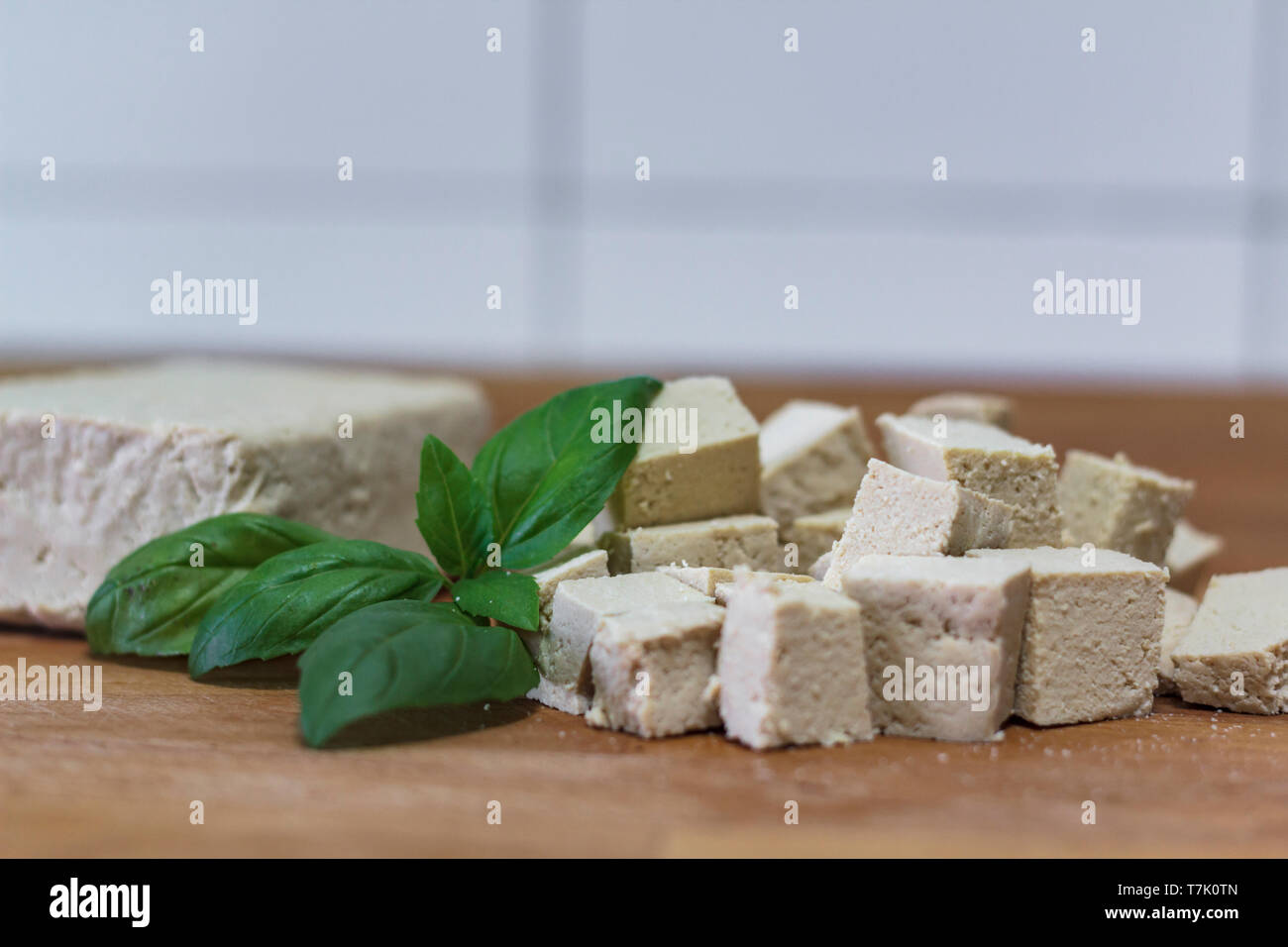 Blocco di tofu e cubetti di tofu sul tagliere di legno Foto Stock