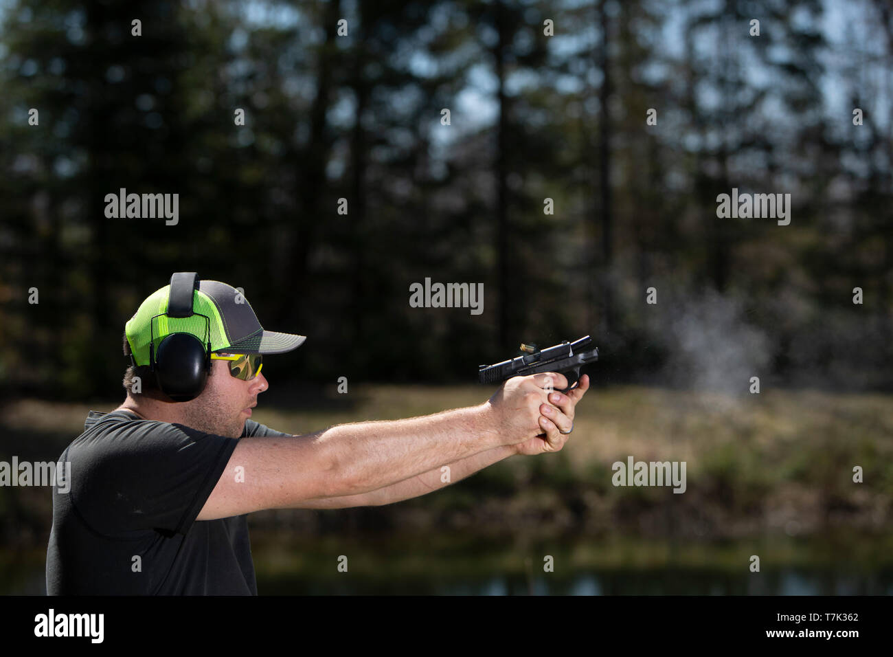 Una cartuccia vuota caso essendo espulso da una pistola come un uomo di germogli. Foto Stock