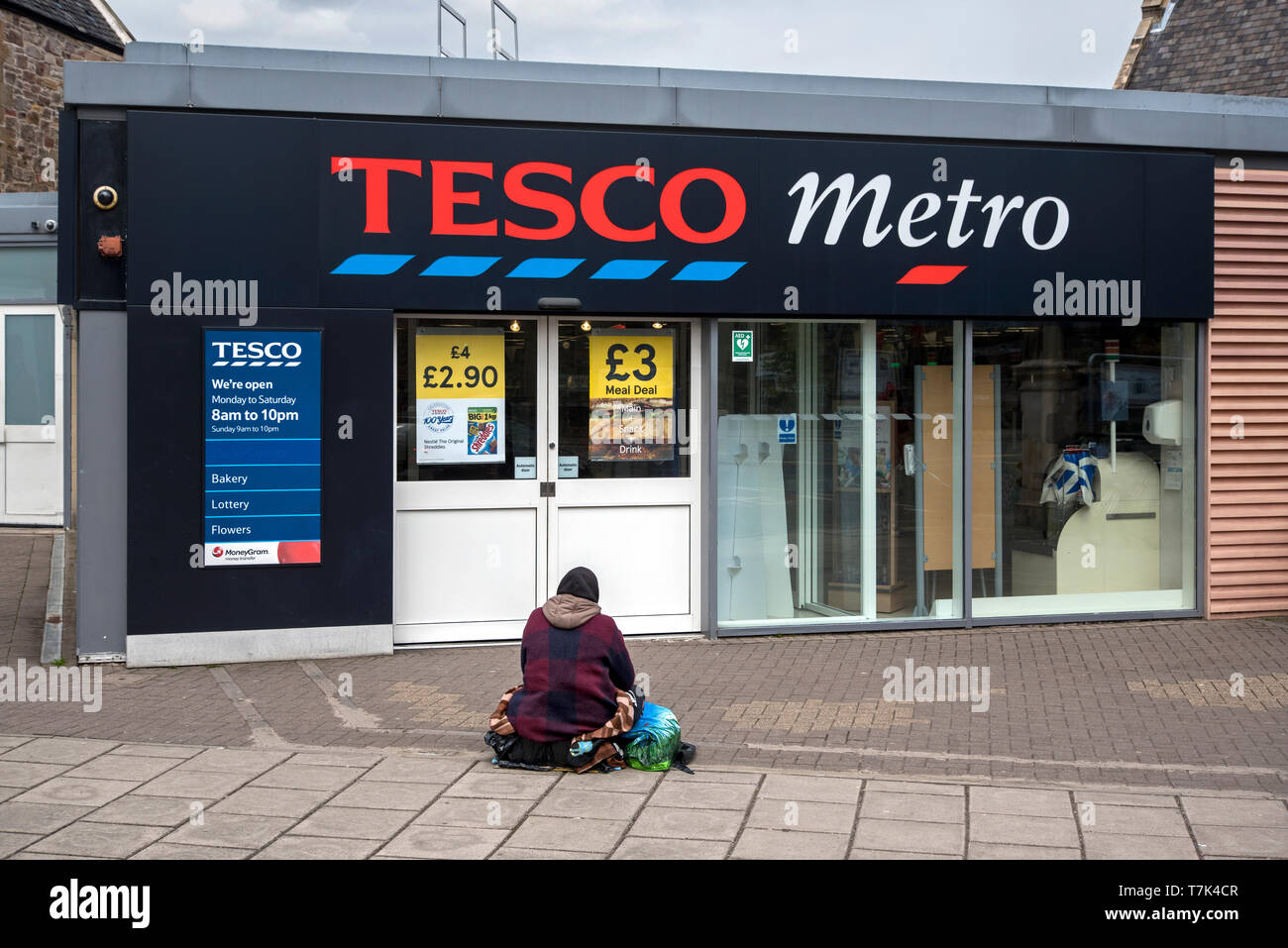 Un mendicante si trova al di fuori della Tesco Metro store al angolo santo, Edimburgo, Scozia, Regno Unito. Foto Stock