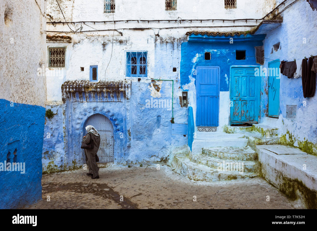 Chefchaouen, Marocco : una donna marocchina passeggiate passato blu-lavato edifici tradizionali nella medina old town. Foto Stock