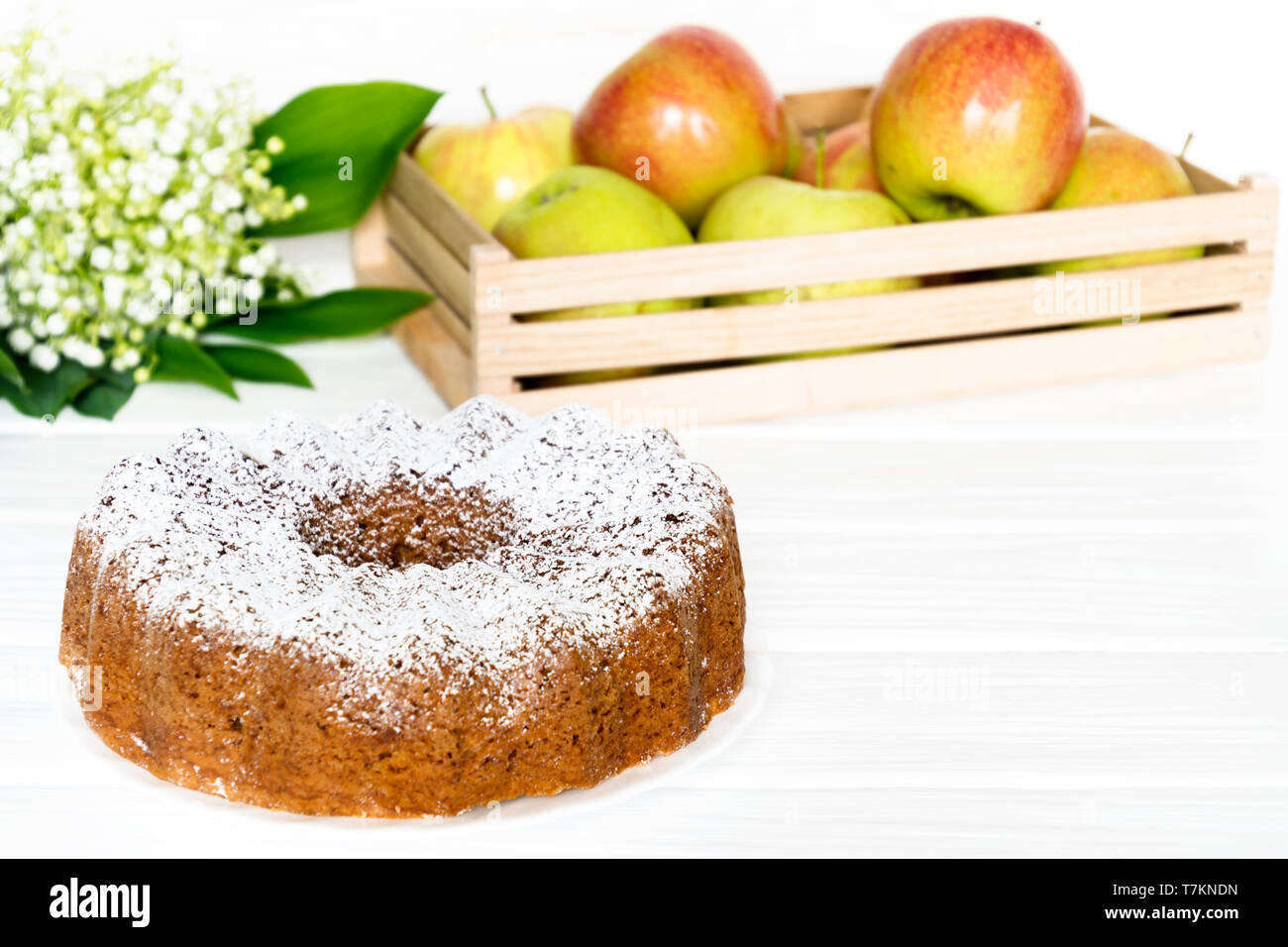 Apple Bundt Cake bianco sul tavolo di legno con le mele e la molla bouquet. Selezionate soft focus Foto Stock