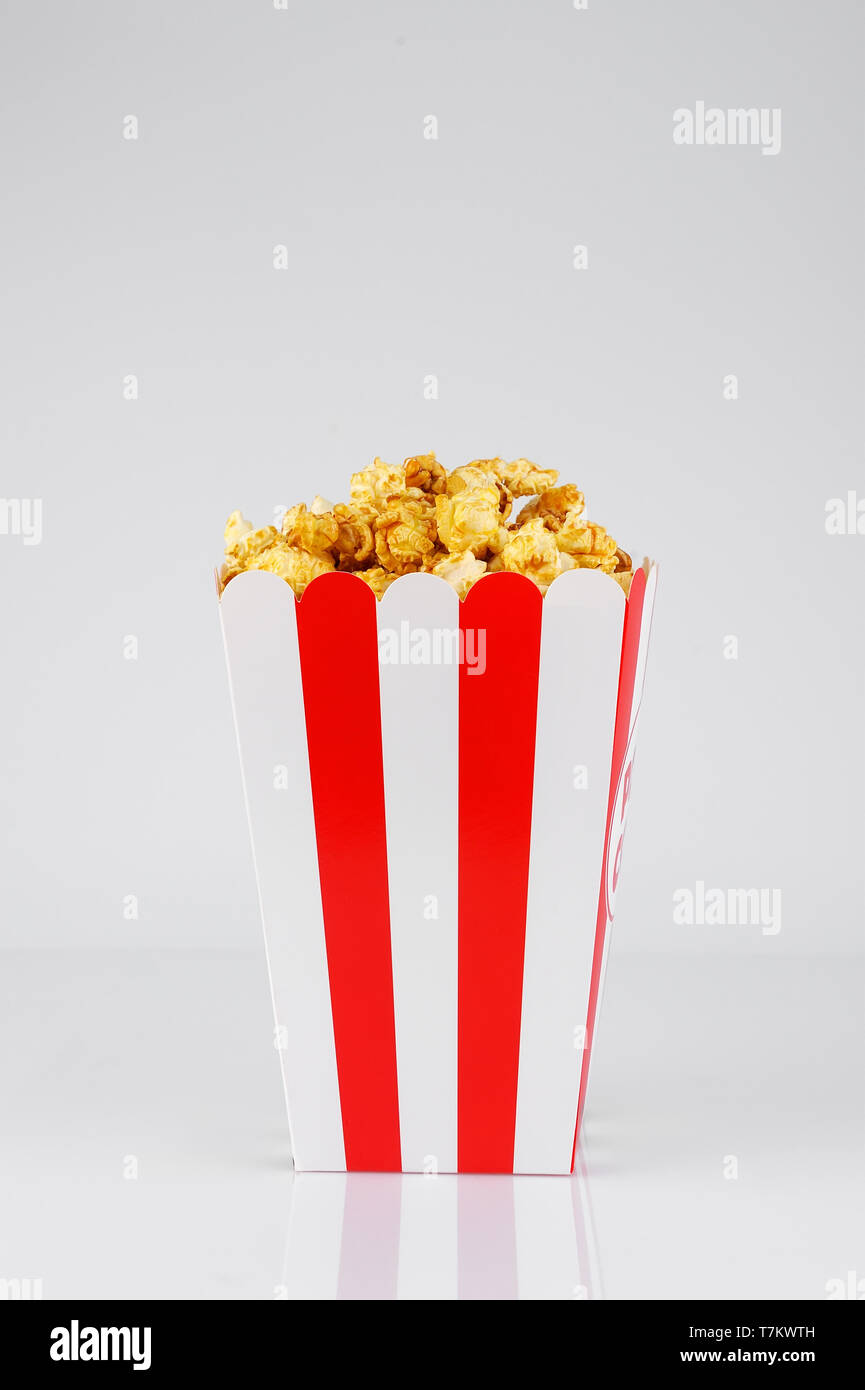 Caramello popcorn in carta a strisce rosse e bianche scatola di linea su sfondo bianco. Snack e cibo per un filmato.L'orientamento verticale. Foto Stock