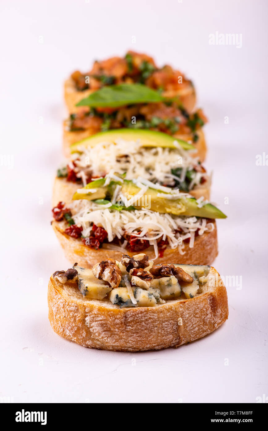 Spaghetti insieme per un aperitivo. Varietà di piccoli panini con pomodori, parmigiano, avocado e noci servita su sfondo bianco Foto Stock