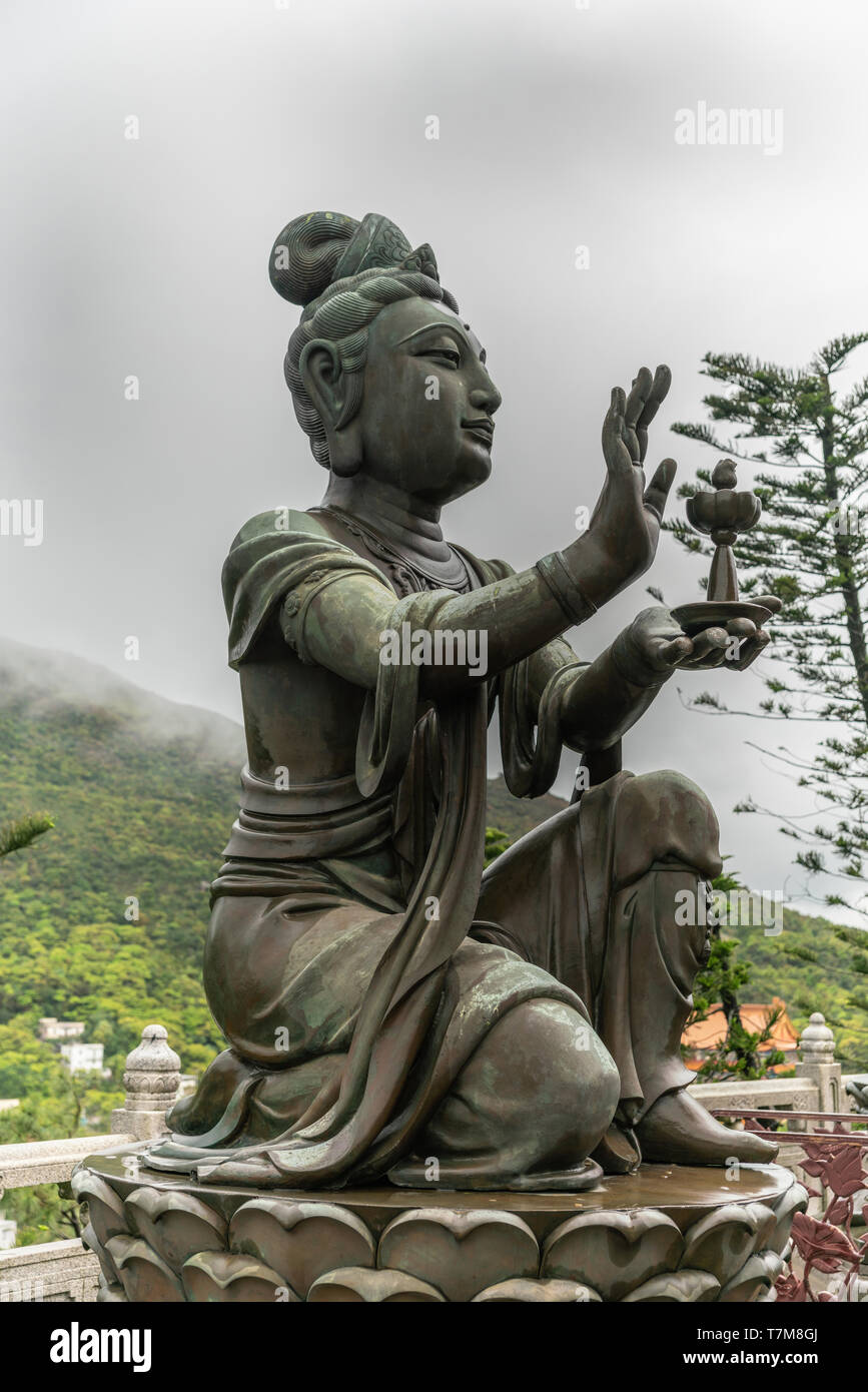 Hong Kong, Cina - 7 Marzo 2019: l'Isola di Lantau. Lato Closeup, uno dei sei deva offre lampada di Tian Tan Buddha. Statua in bronzo visto dalla parte anteriore con Foto Stock