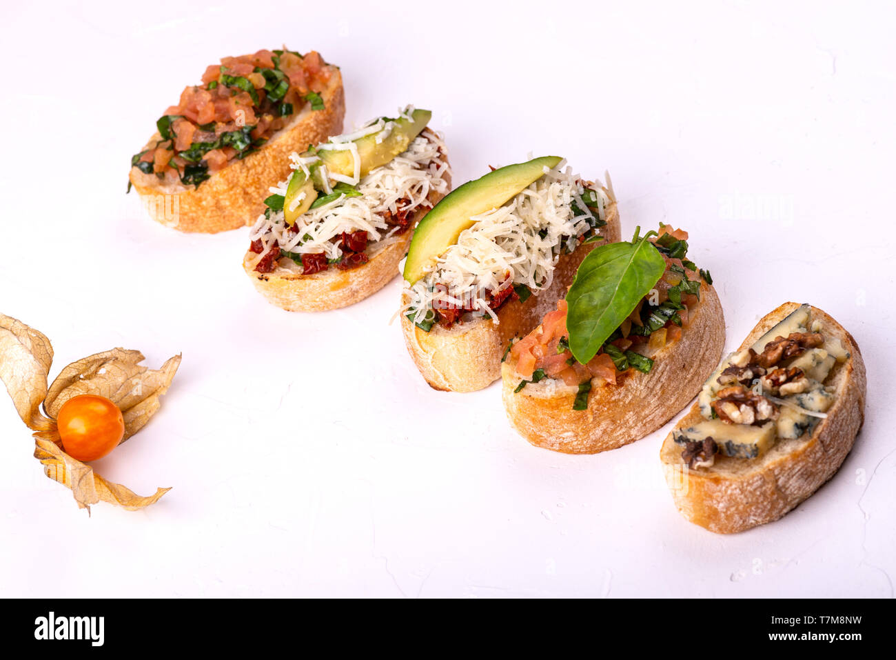 Varietà di crostino con hummus, pomodoro, avocado, formaggio, noce e verdure fresche su sfondo bianco. Vista dall'alto di snack sani concetto. Foto Stock