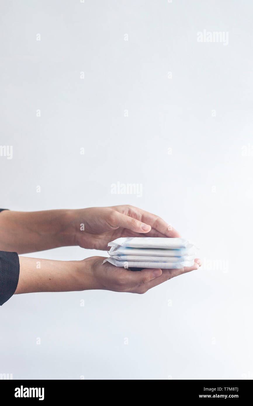 La femmina prodotti igienici. Donna di mano che tiene una pila di assorbenti igienici contro uno sfondo bianco. Periodo giorni concetto mostra menstru femminile Foto Stock