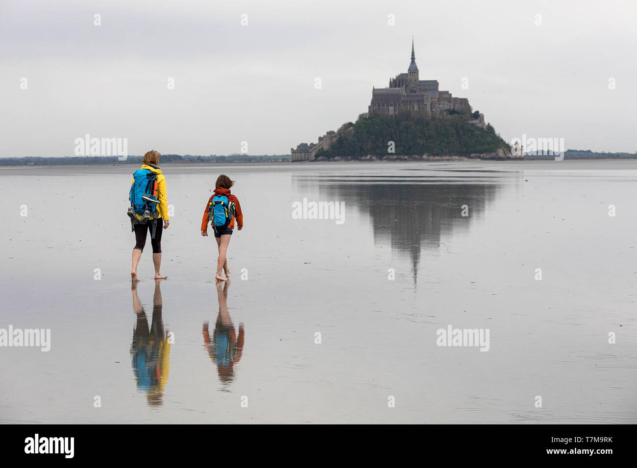 Donna e bambino escursioni attraverso la baia di Mont Saint Michel abbey, bella riflessione dell'isola, in Normandia, Francia Foto Stock