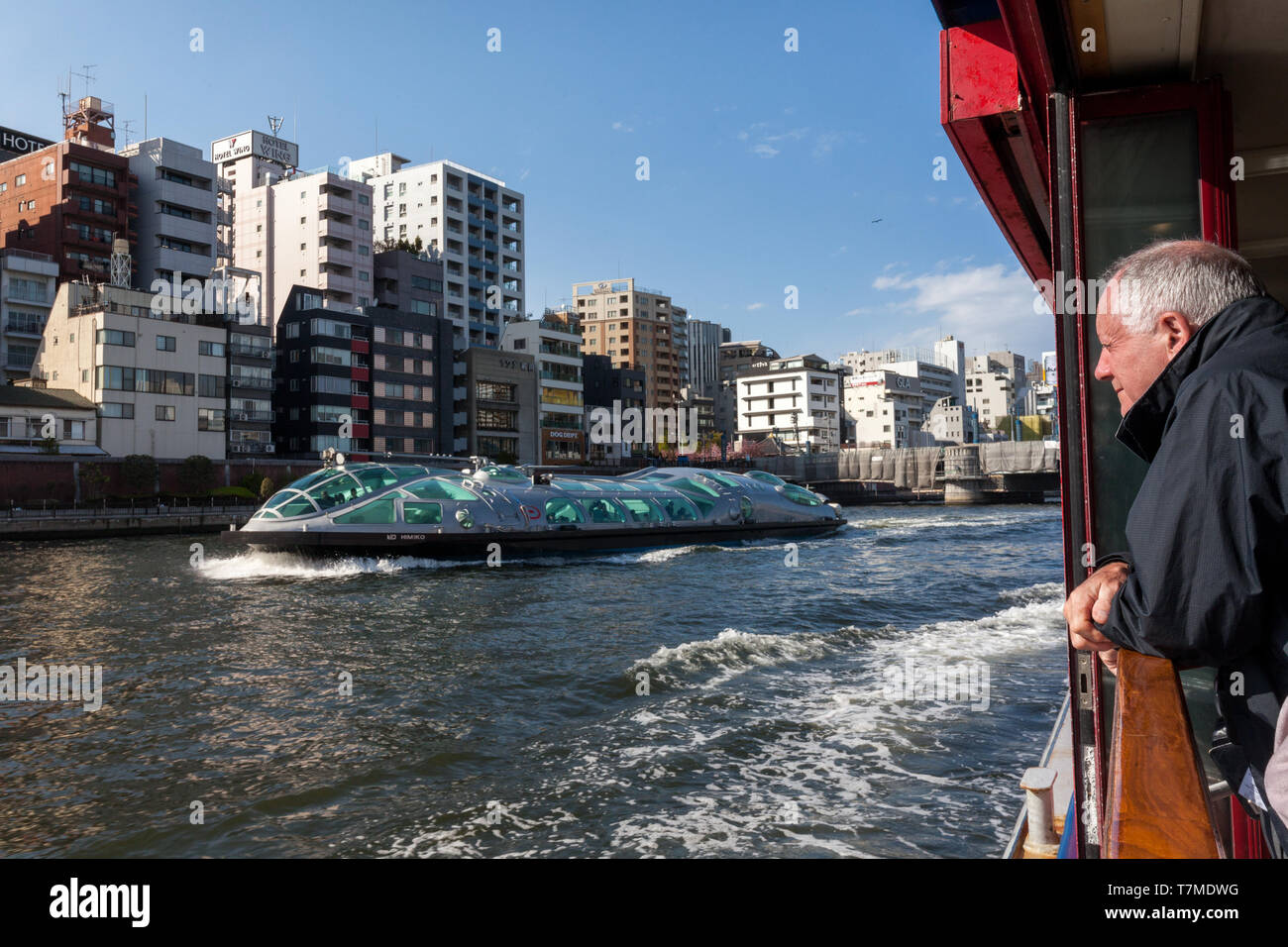 Un turista maschio bianco guarda le distintive barche di crociera di fiume Himiko dalle sue proprie barche di crociera di Sumida vicino Asakusa a Tokyo, Giappone. Foto Stock