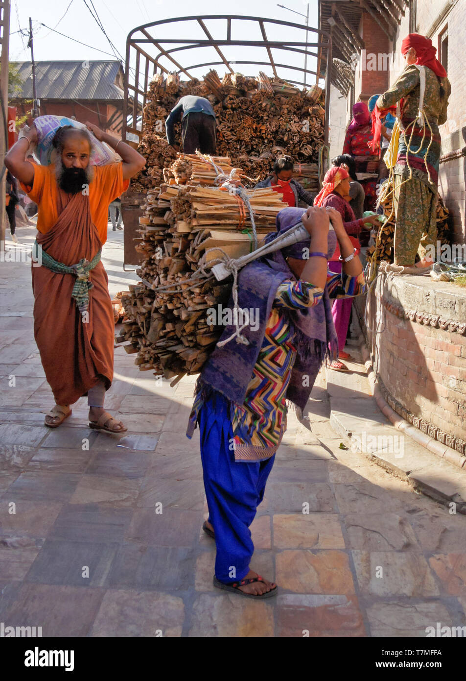 Lavoratori scaricare la legna da ardere da un carrello e portarlo al funerale ghats, Pashupatinath tempio indù, Valle di Kathmandu, Nepal Foto Stock