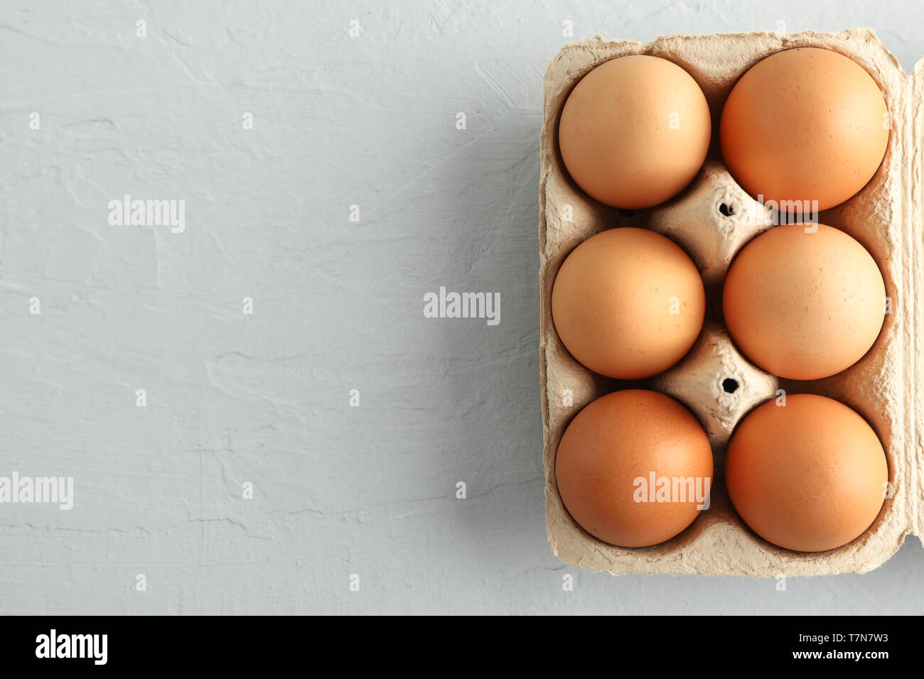 Le uova di gallina in scatola di cartone su sfondo grigio, spazio per il testo Foto Stock