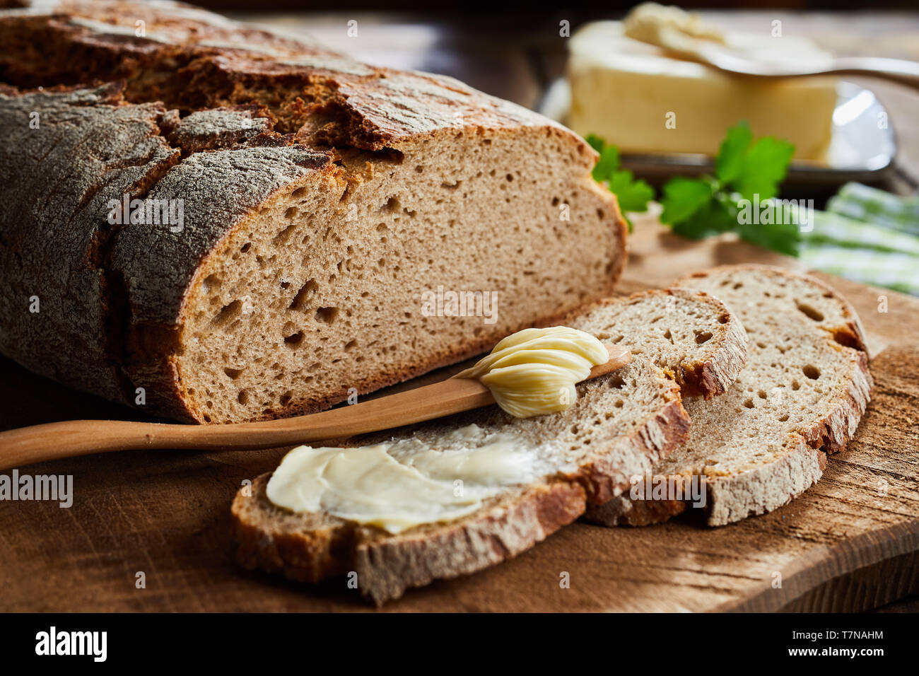 Imburrato fetta di pane di segale con crostini di pane tagliato per mostrare la consistenza del pane in un angolo basso vicino la vista su di un tagliere di legno Foto Stock
