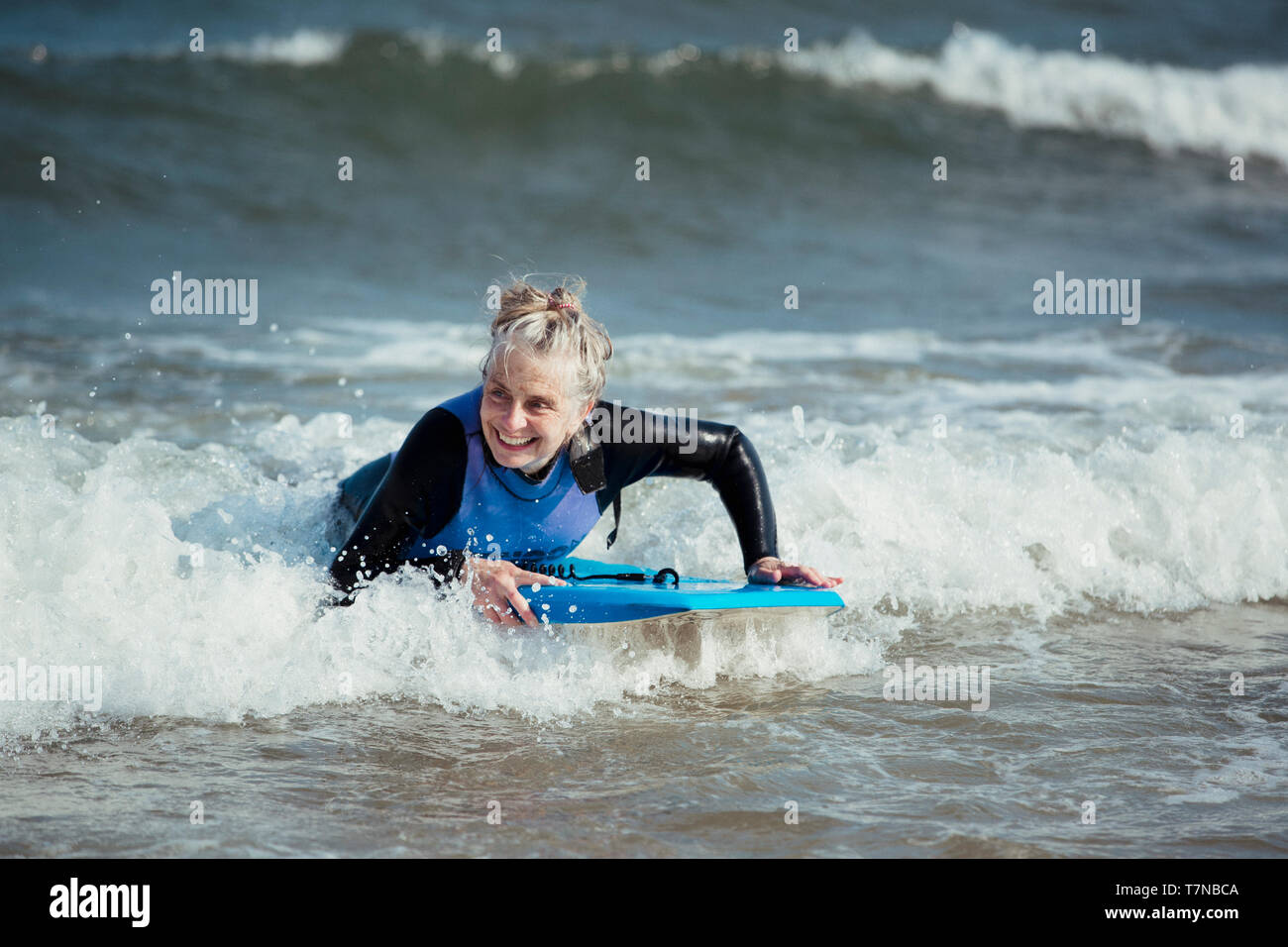 Donna matura per divertirsi su un bodyboard in mare. Foto Stock