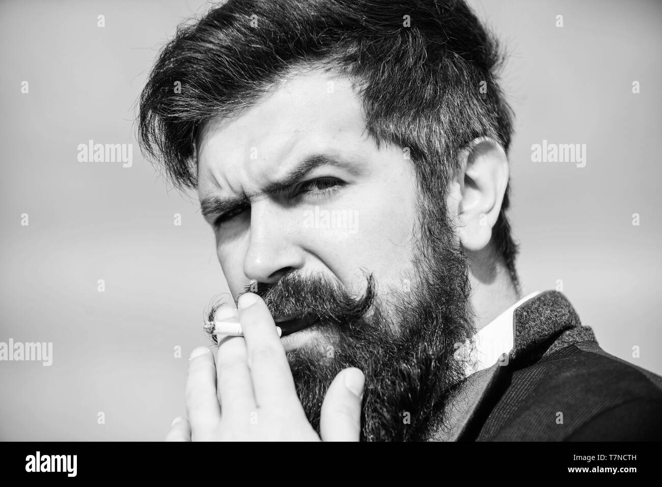 Nel suo proprio stile. Uomo Barbuto di fumare la sigaretta. fumo. brutale caucasian hipster con baffi. Coppia hipster con la barba. Imprenditore contro il cielo. In futuro il successo. Maschio moda formale. Foto Stock