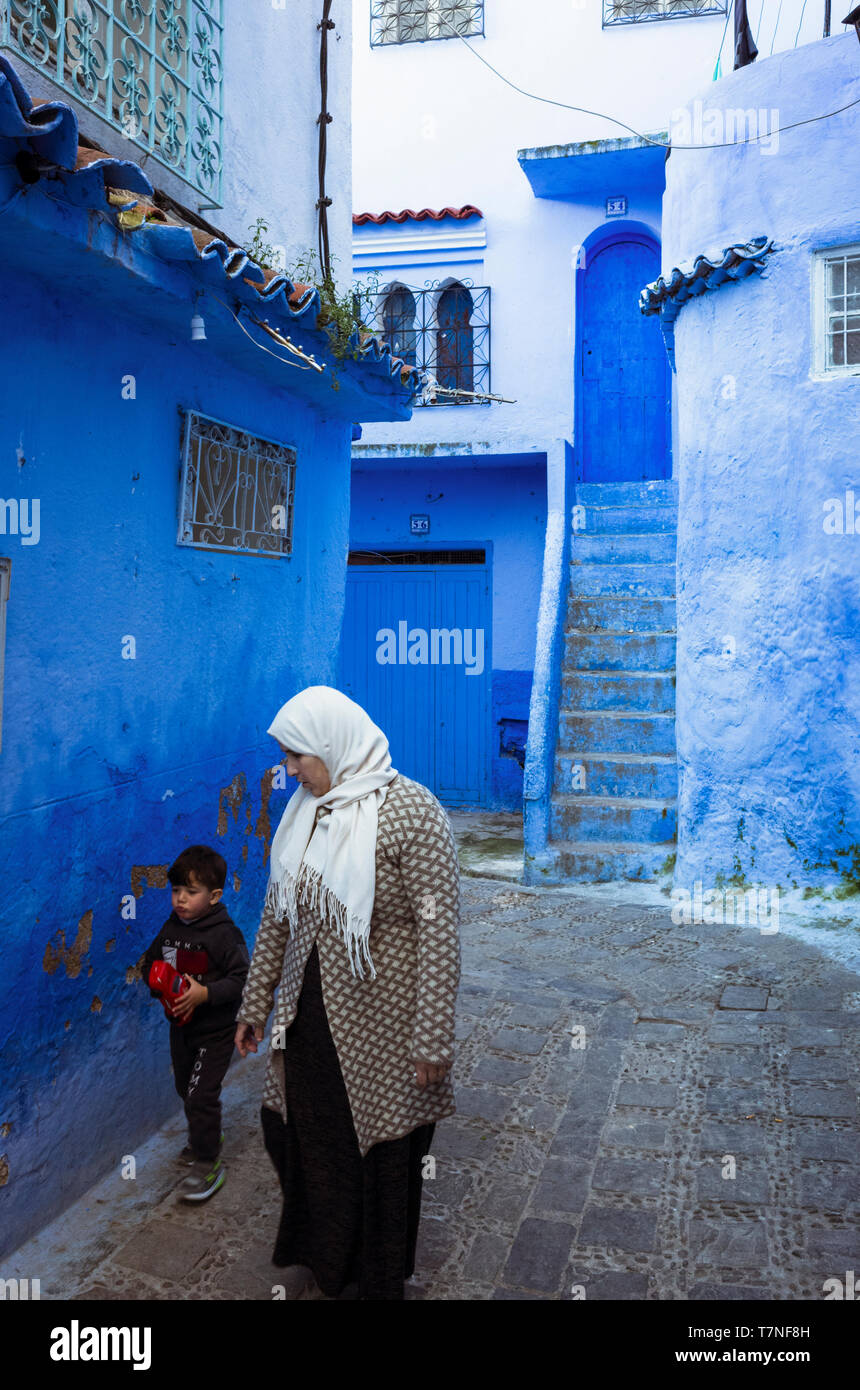 Chefchaouen, Marocco : una donna marocchina e un bambino a piedi nel blu-lavato medina old town. Foto Stock