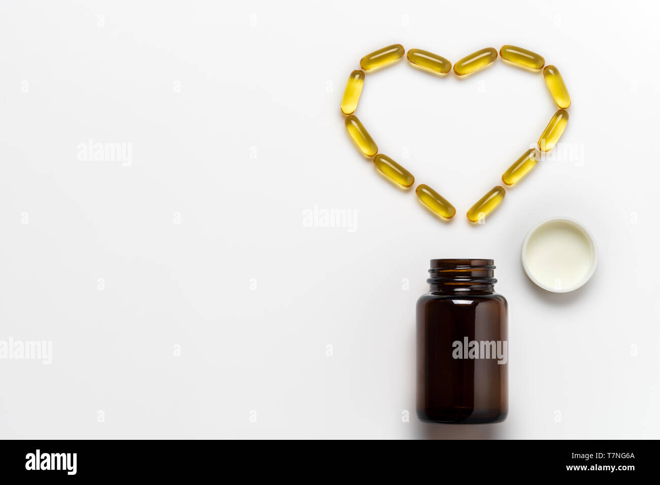 Olio di pesce capsule è disposto in forma di cuore su sfondo bianco. Concetto di cura e salute. Vista superiore e copia spazio per il testo. Foto Stock