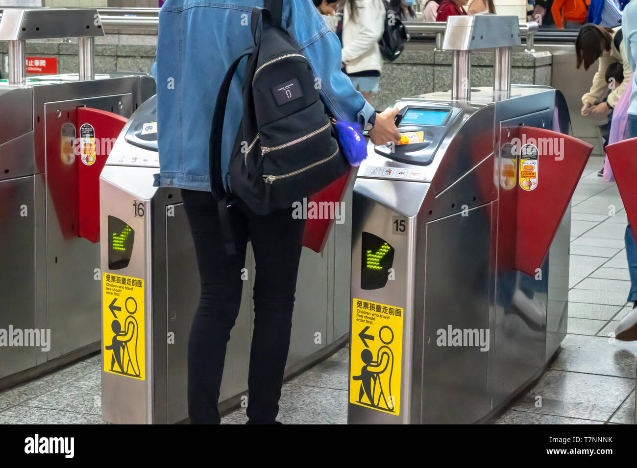Passeggeri a piedi attraverso il pagamento della tariffa della zona di porta di uscita di Taipei dalla stazione della metropolitana, mentre toccando il loro trasporto pubblico schede di IC, in Taipei, Taiwan Foto Stock